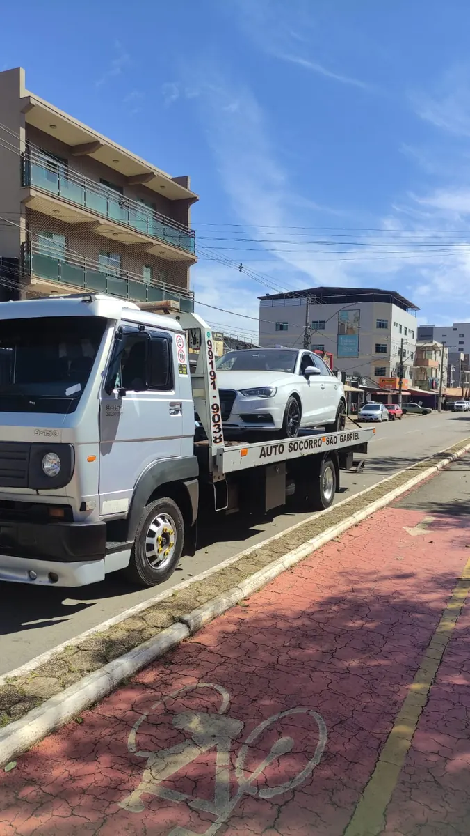 Sedã branco sobre o caminhão-plataforma identificado da Auto Socorro São Gabriel em avenida
