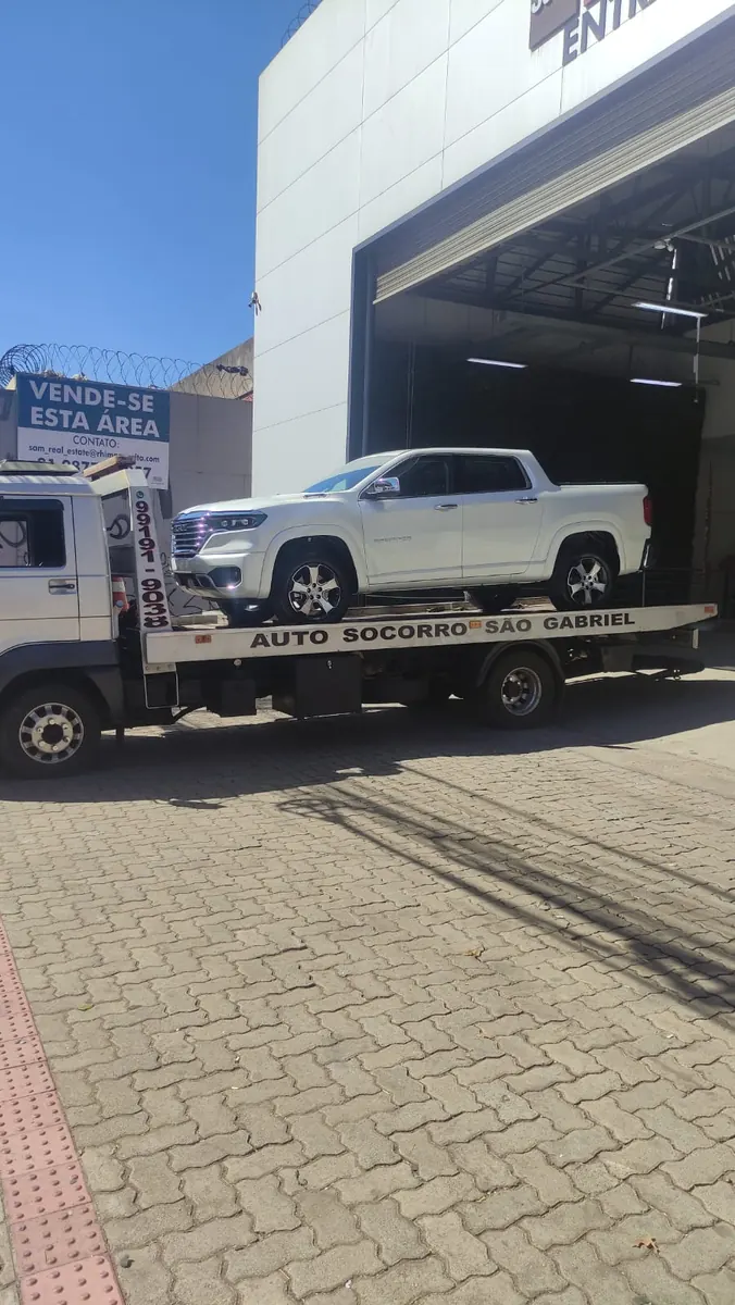 Caminhão-plataforma da Auto Socorro São Gabriel transportando uma picape branca em via urbana